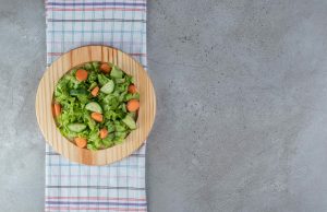 A wooden board with vegetable salad on a tablecloth . High quality photo