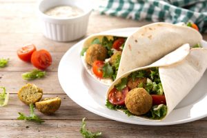 Tortilla wrap with falafel and vegetables on wooden table